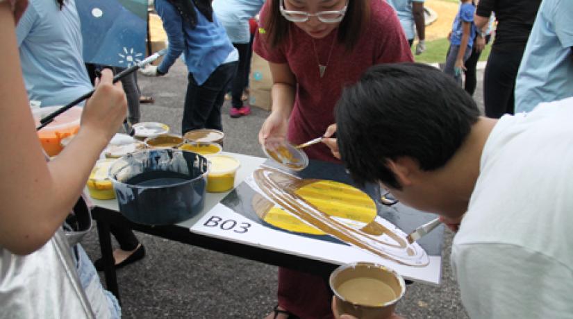 TEAMWORK: Participants painting one of several mysterious canvases that were later fitted together to reveal a beautiful mural to commemorate World Autism Awareness Day 2016.