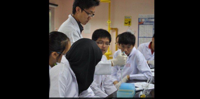 The "FBI Agent" aka BSc Biotech student Felius Yuseli (standing), assisting the student participant group he was assigned to. He is demonstrating how to use a micropipette, an integral equipment of molecular biotechnology. The "FBI Agent" aka BSc Biotech student Felius Yuseli (standing), assisting the student participant group he was assigned to. He is demonstrating how to use a micropipette, an integral equipment of molecular biotechnology.