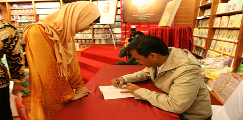 Muhamad Hafiz bin Ismail signing a copy of his book ‘Life Through My Eyes’ for a member of the audience