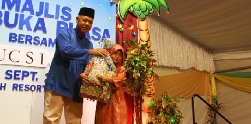 Tuan Haji Ab Khalid distributes a Raya hamper to the daughter of one of the guests during the giveaway.