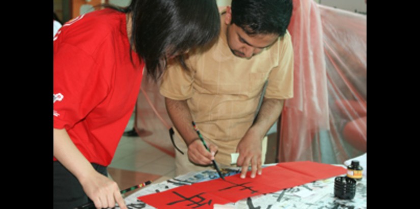 A UCSI University international student being taught Chinese calligraphy by a CCS member