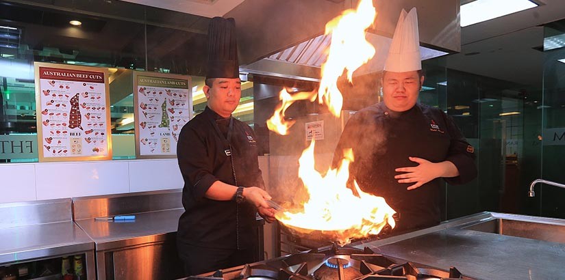 Assistant Professor Mohamed Fadzly (left) showing off some of his exceptional cooking techniques as Mohd Aiman (left) looks on.