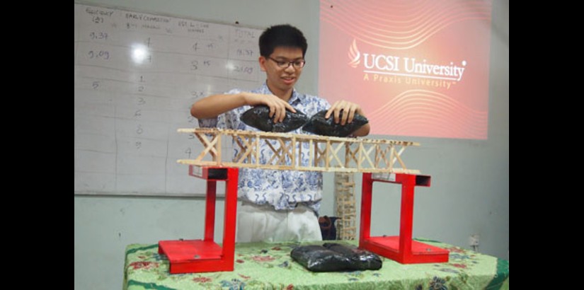 TEST OF STRENGTH: A student from SMA Yos Sudarso putting loads on his team’s model bridge to test its strength during the ‘Creative Bridge Challenge Workshop’.