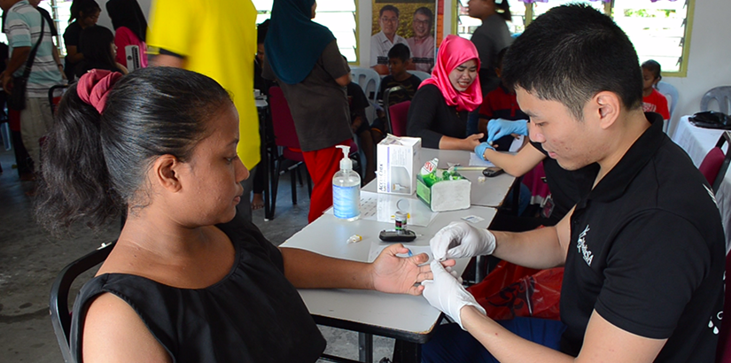 One of the volunteers from UCSI MedicSA checking the blood glucose level of a fellow villager.