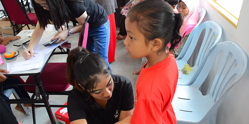 Volunteer of UCSI MedicSA measuring the waist-to-hip ratio of a child.