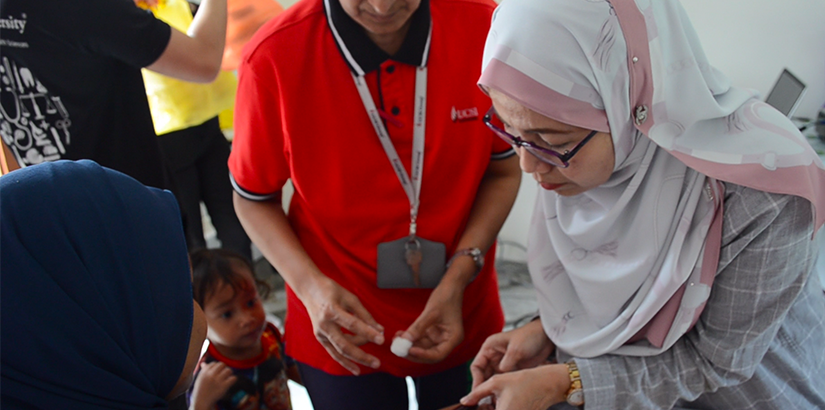 Dr Rafezah and Dr Kyu Kyu Win helping as volunteers to draw blood from the villagers.