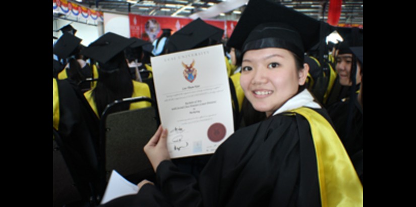 A student proudly displaying her university degree 
