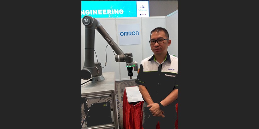OMRON booth representative with equipment.