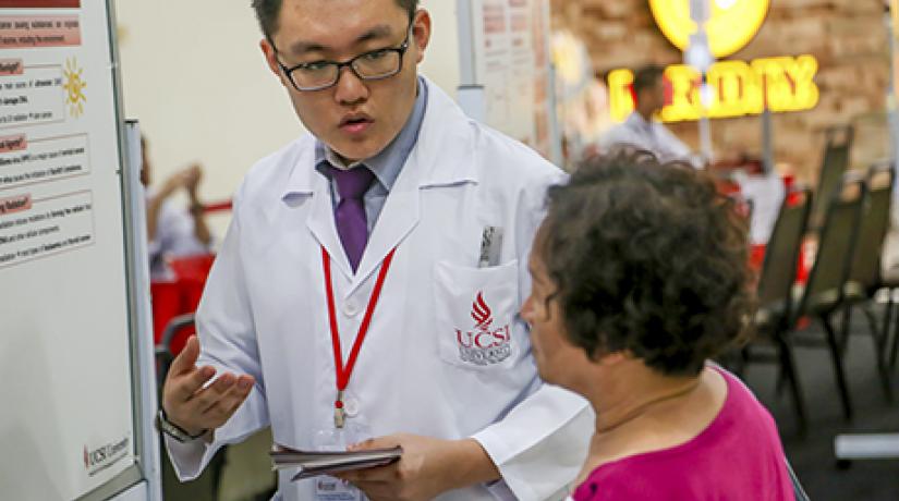 RAISING AWARENESS: A UCSI pharmacy student explaining to a member of the public the many factors leading to cancer.