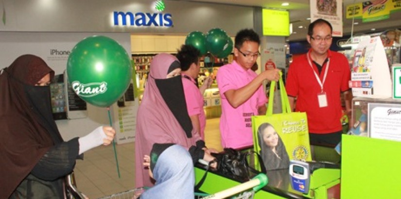 Mr OK Tan, a lecturer at UCSI University's KT campus and volunteer Interactors helping a family put their shopping into a reusable shopping bag.