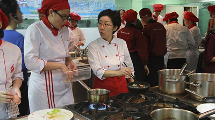  TOTAL FOCUS: Seoul University (Food Science and Nutrition department) Adjunct Professor Kim Kyung Mi (right) giving a student pointers on cooking bibimbap.