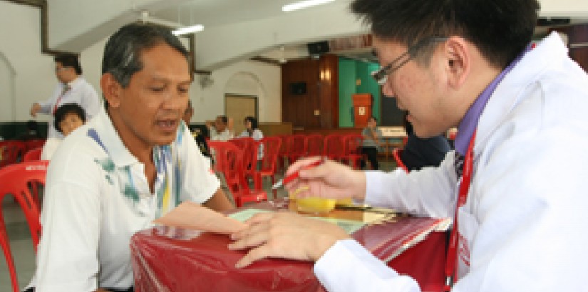 A UCSI University Pharmacy student explaining the results of a Body Fat test to a member of the public