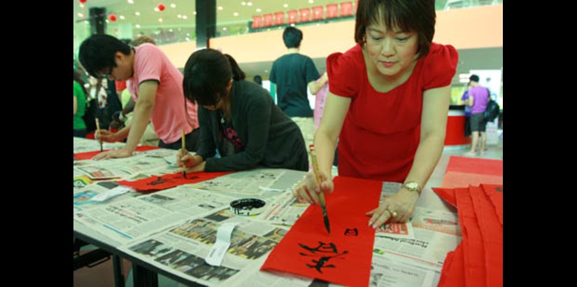  Ms Margaret Soo writes an auspicious Chinese New Year greeting during the Chinese Calligraphy competition.