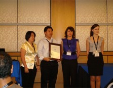 Sim Kwan Choo stands on stage after receiving his PASS Leader award